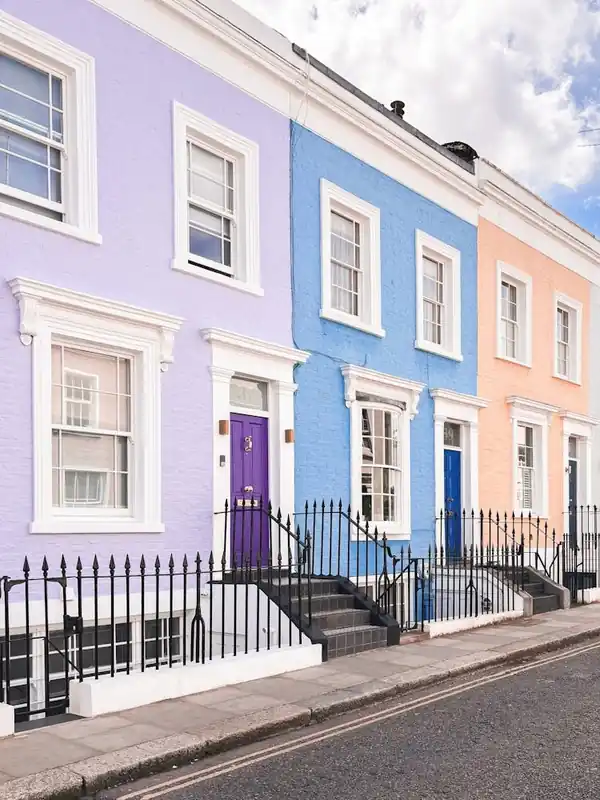 London, England I Pastel facades of Notting Hill streets captured in colorful British architecture photography to the purple blue and pink dollhouse aesthetic of an everyday lifestyle londoner street scene Trusted Brand